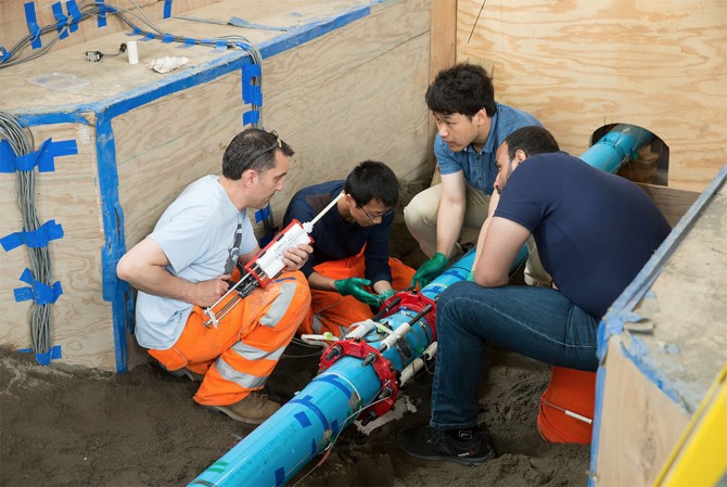 Researchers glue fiber-optic sensors to a test pipe in Cornell’s Geotechnical Lifelines Large-Scale Testing Facility