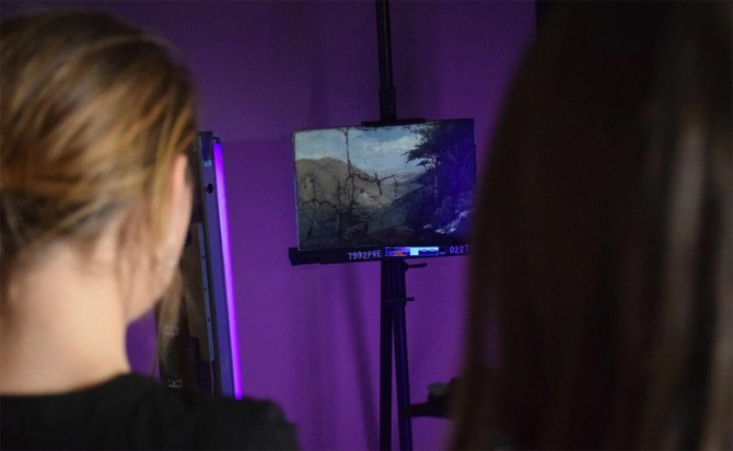 Students examine a painting under ultraviolet light