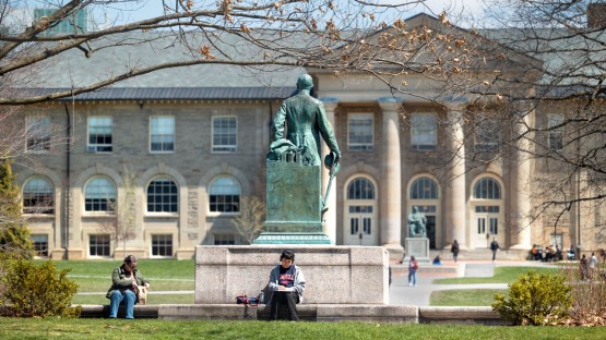 Students enjoy the sun on the Arts Quad by the Ezra Cornell Statue.